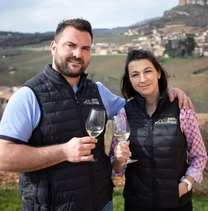 To mennesker fra Domaine Trouillet med vinglas foran vinmarkerne